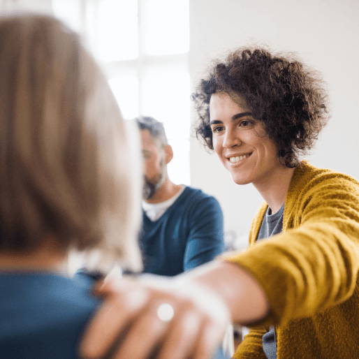 A woman reaches out to support another woman at a group therapy session