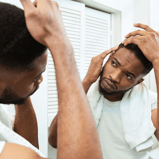 A man in his twenties looks in the bathroom mirror, checking his hair