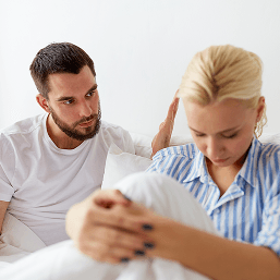 A man reaches out to comfort a woman who is looking down sadly