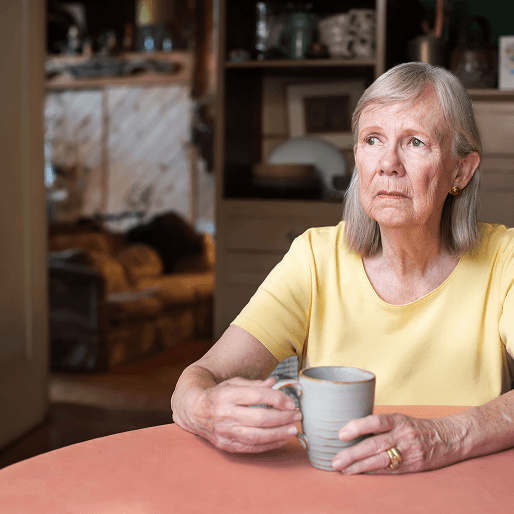 A concerned looking woman sits with a cup looking away