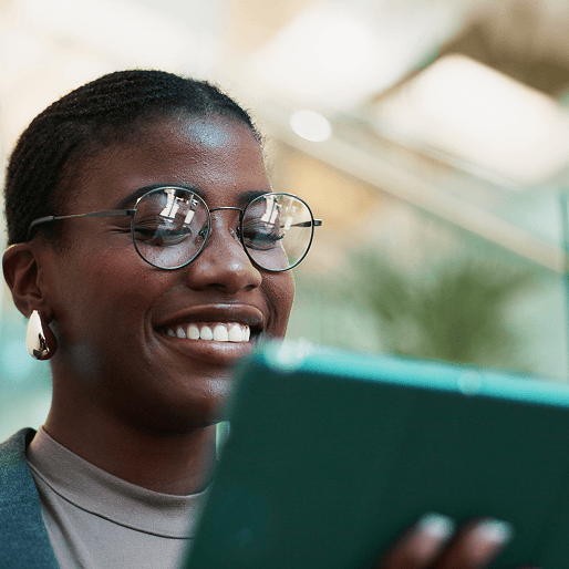 A young woman smiles as she focuses on the tablet in her hand